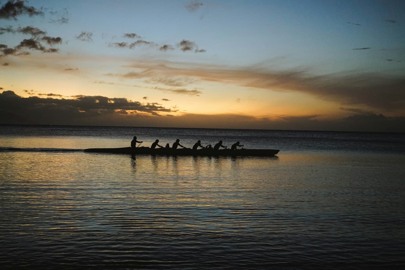 Rowing crew pulling together on the water at sunset